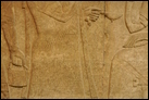 Сцена суда (фрагмент; см. также предыд. и след. фото). Нимруд, ок. 865-860 гг. до Р.Х. Британский музей. WA 124564-6. Царь Ашшурнацирапал восседает среди слуг. Эта группа окружена парой крылатых духов-хранителей. Мастерство этих панелей превосходно: одежда изобилует детально проработанными прорезями, на обуви сохранились следы краски.