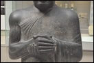 Статуя Гудеа. Месопотамия, XXII в. до Р.Х. Британский музей. ME 122910. Гудеа — царь г. Лагаша, правил ок. 2150 г. до Р.Х. Царь изображен как верный служитель и посланник своего бога. Почтительная поза, когда руки сложены впереди, а также одеяние, накинутое через плечо, отражают традицию обетных статуй более ранней эпохи.